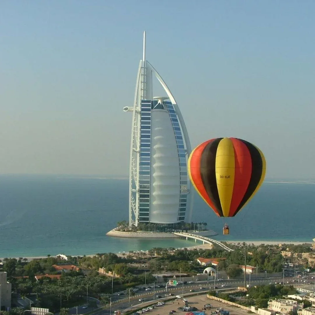Hot air balloon flying over Dubai desert with Burj Al Arab in background