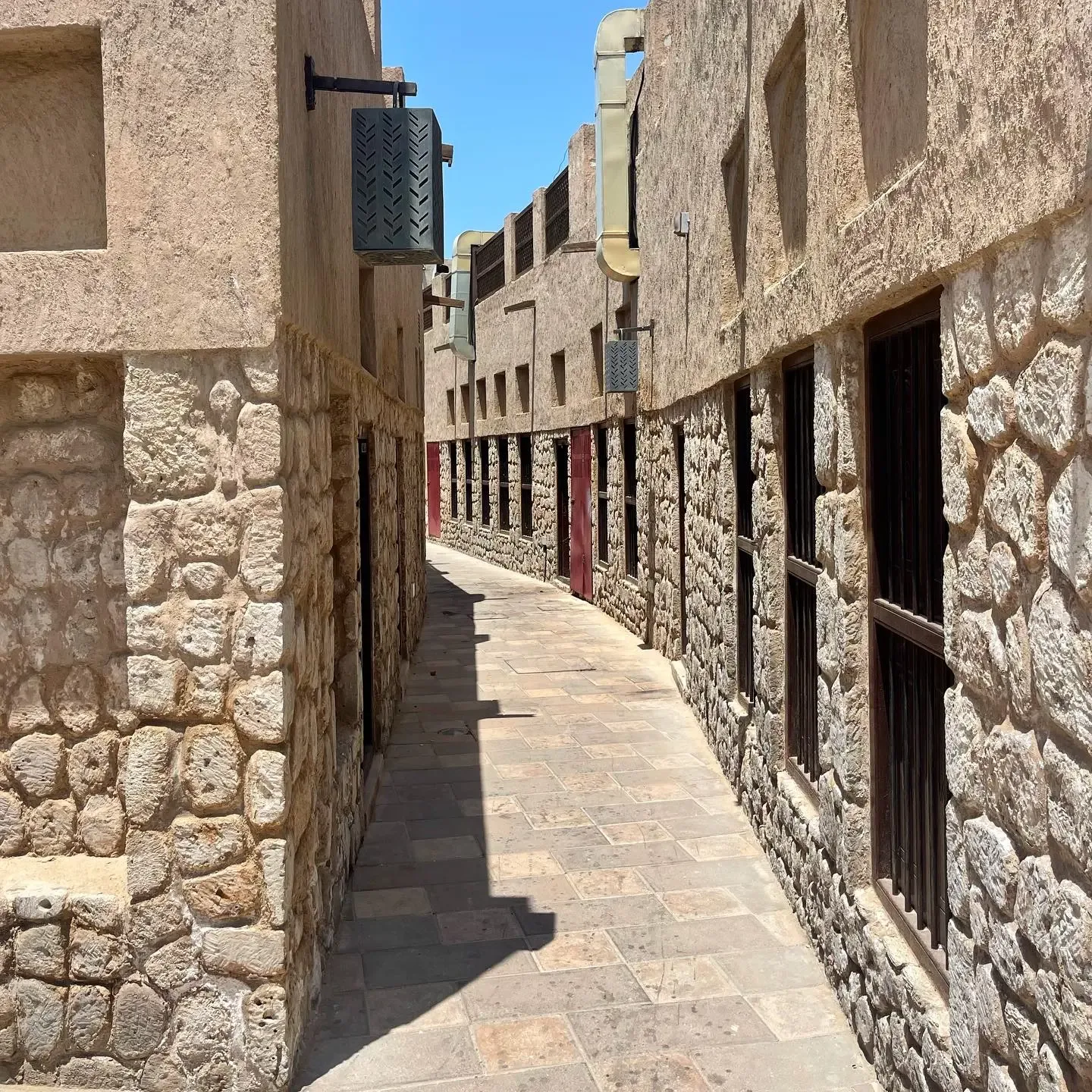 Narrow heritage walkway at Al Shindagha Museum with traditional stone walls and wooden doors