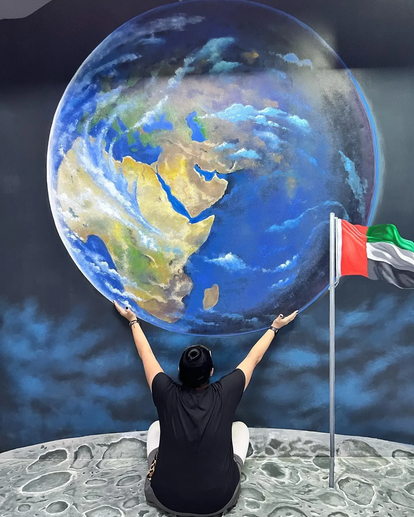 Visitor holding giant globe with UAE flag at 3D World Selfie Museum Dubai
