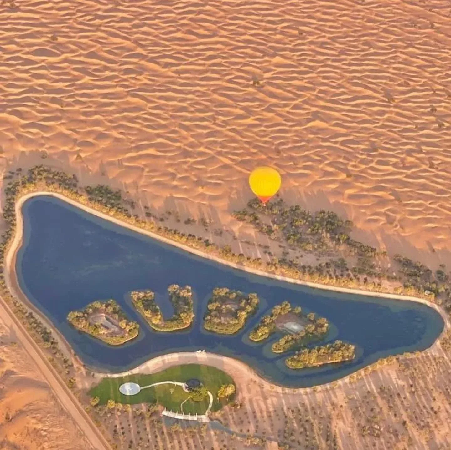 Aerial view of hot air balloon flying over Dubai desert and landscaped lake