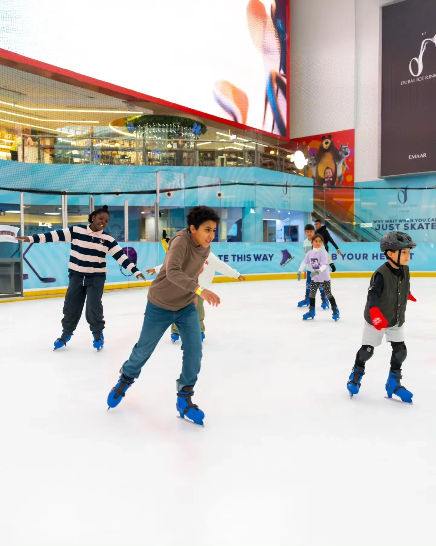 Visitors ice skating at Dubai Ice Rink in Dubai Mall with children learning to skate