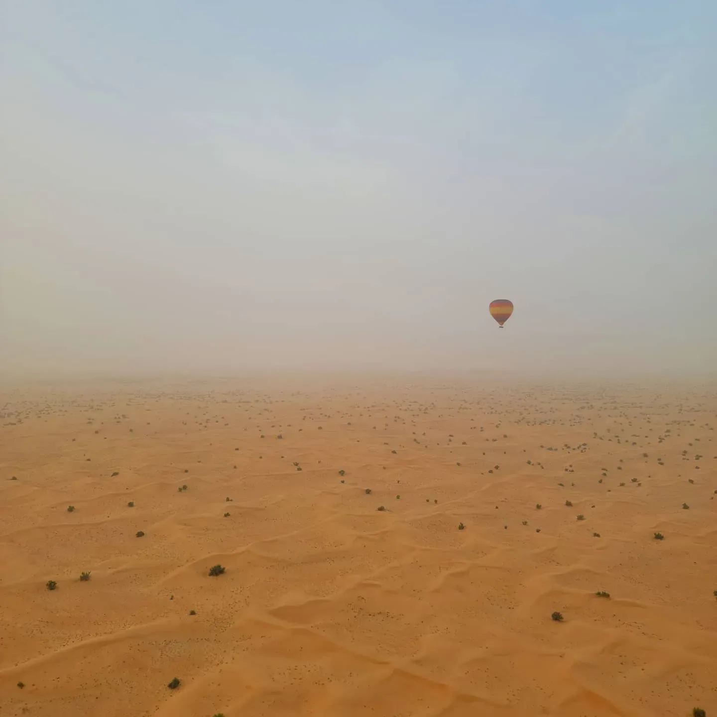 Hot air balloon flying over vast Dubai desert landscape