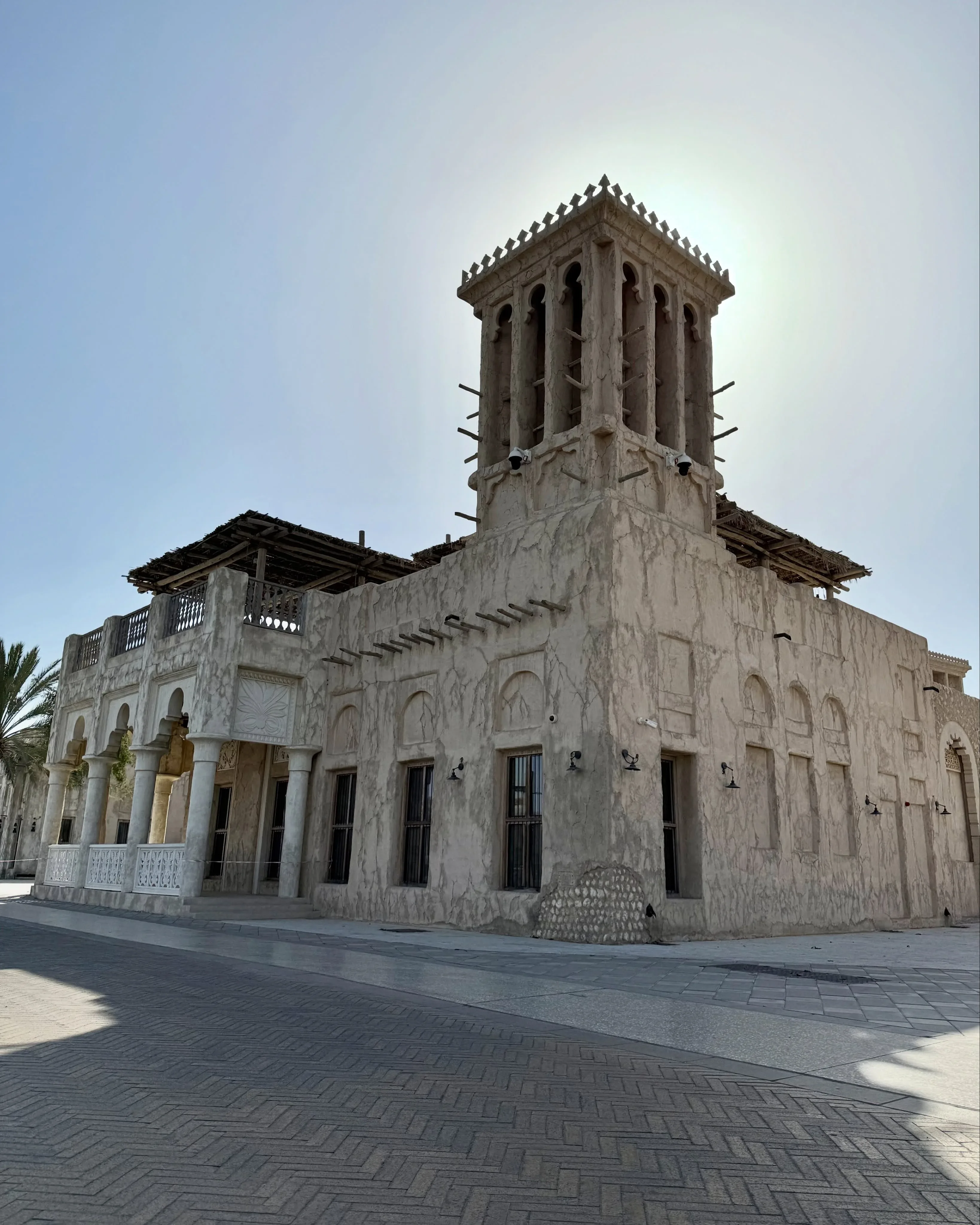 Traditional Emirati heritage building featuring a distinctive wind tower and arched windows