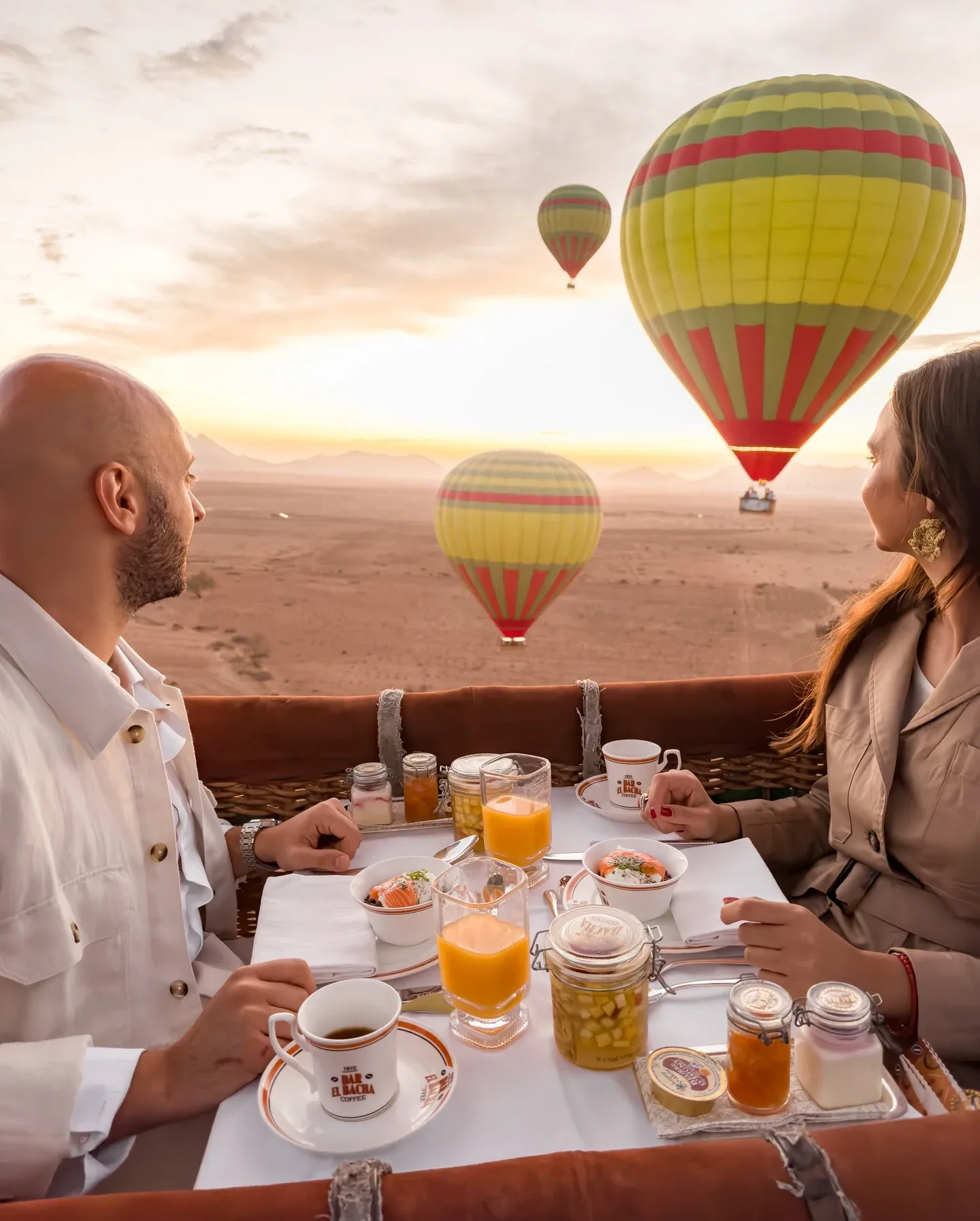 Couple enjoying breakfast in a hot air balloon above the desert at sunrise