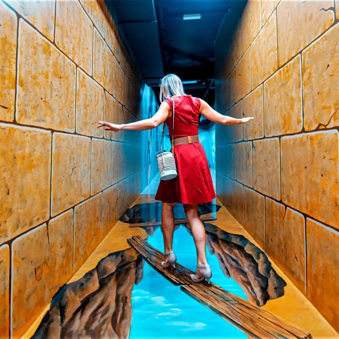 Woman walking across 3D bridge illusion at 3D World Selfie Museum Dubai