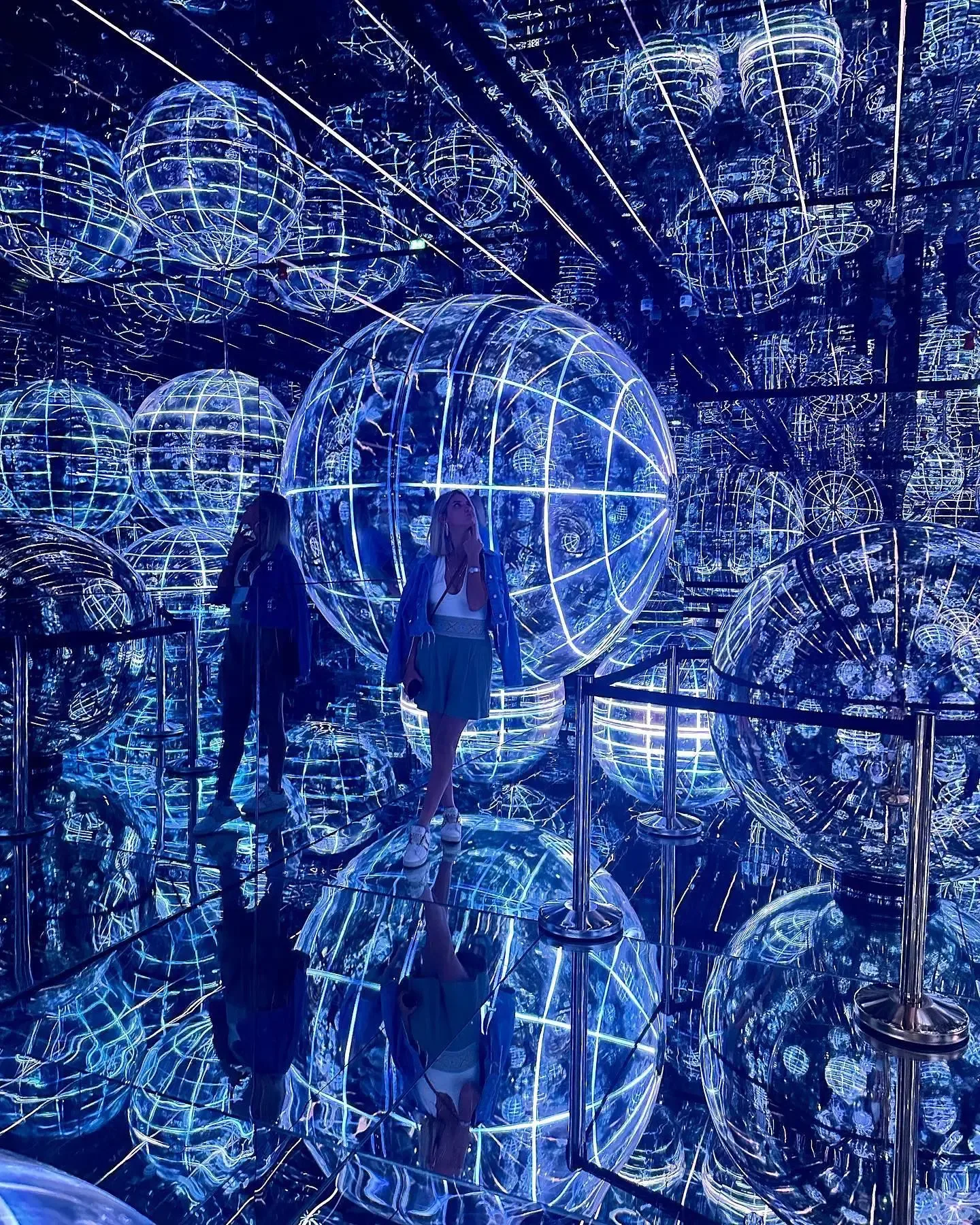 AYA Universe Dubai visitor surrounded by glowing blue spherical digital projections in a mirrored room