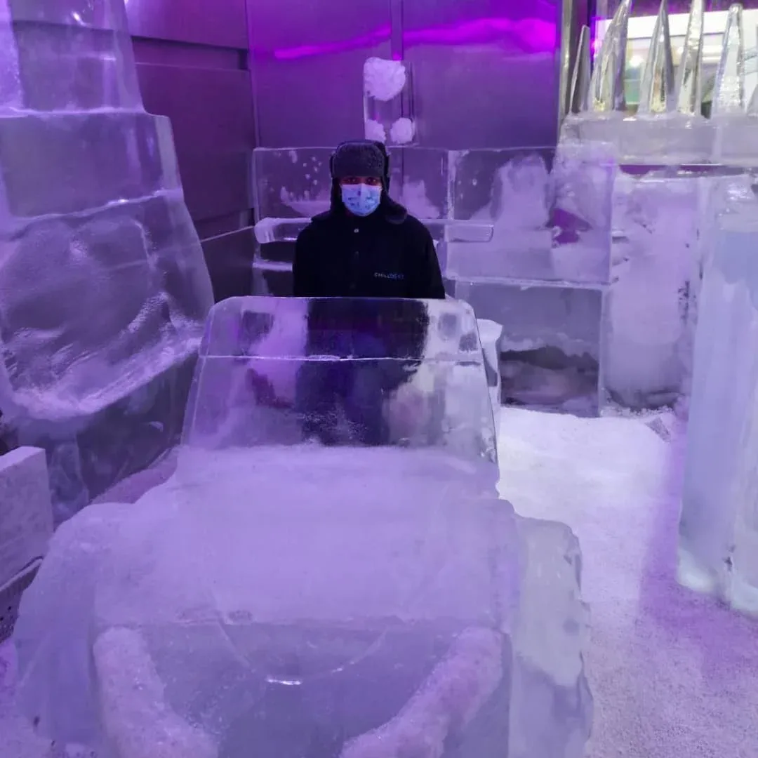 Visitor sitting on an ice chair inside the frozen Chillout Ice Lounge Dubai