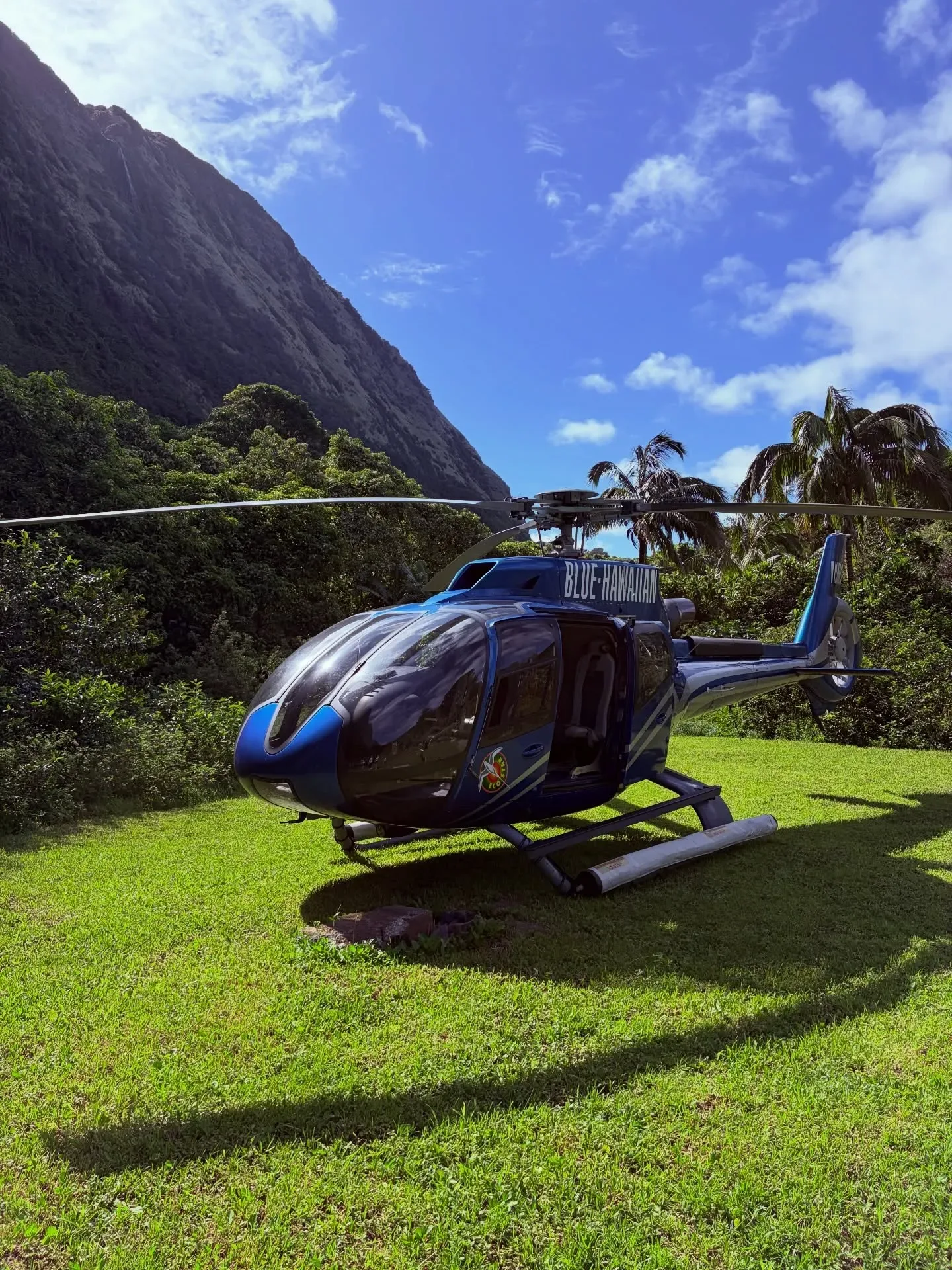 Helicopter parked at a helipad with blue sky and clouds