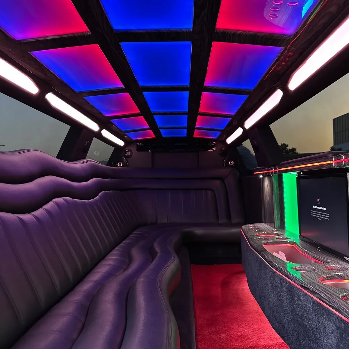 Spacious limousine interior with leather seating and multicolor ceiling lights