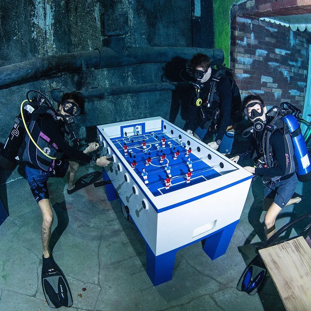Divers playing foosball inside the underwater city at Deep Dive Dubai