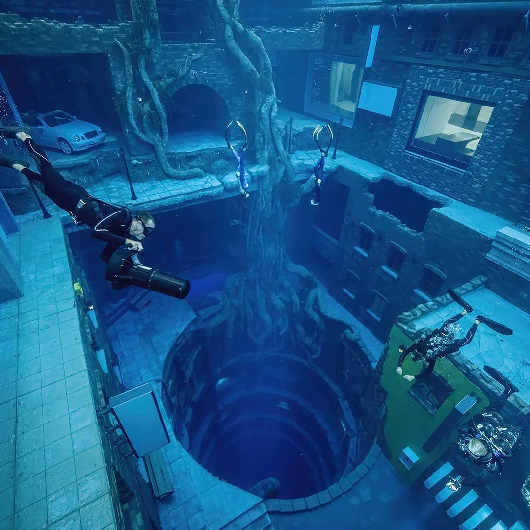 Scuba divers exploring the submerged city and deep pool at Deep Dive Dubai